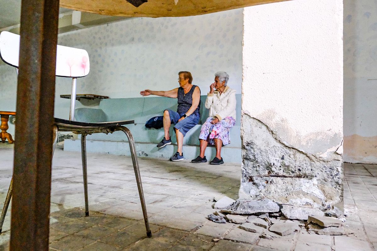 Una vista del daño de un pilar mientras unas vecinas conversan.