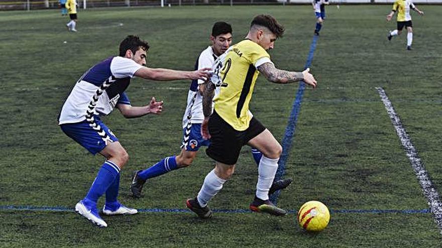 Riccardo Bertolio, que va anotar el primer gol del seu equip, és defensat per dos jugadors del Sabadell B