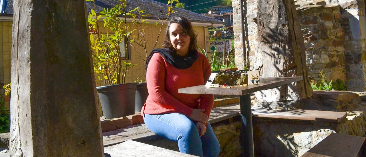 Alba Gutiérrez, sentada a la sombra de una panera, con parte de su trabajo, en Quirós.