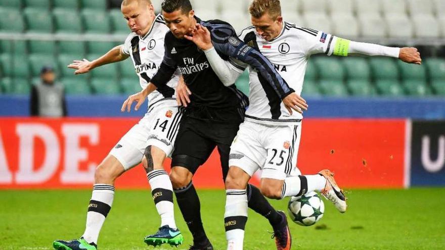 Cristiano Ronaldo, defendido por dos jugadores del Legia en el partido disputado anoche.