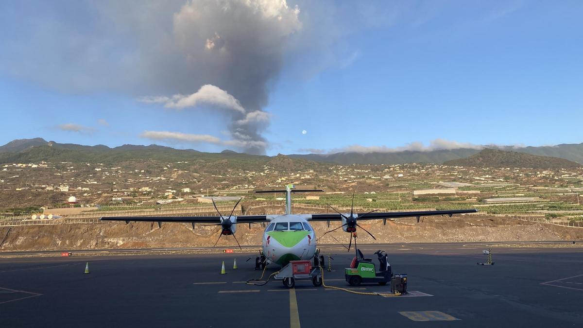 Archivo - Un avión de Binter en la pista del aeropuerto de La Palma, con el volcán en erupción al fondo