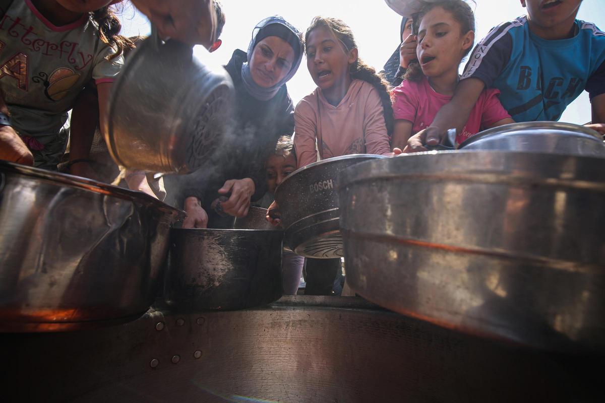 Un grupo de palestinos intenta obtener alimentos repartidos por una organización caritativa en la ciudad de Gaza, en el norte de la Franja de Gaza (archivo)