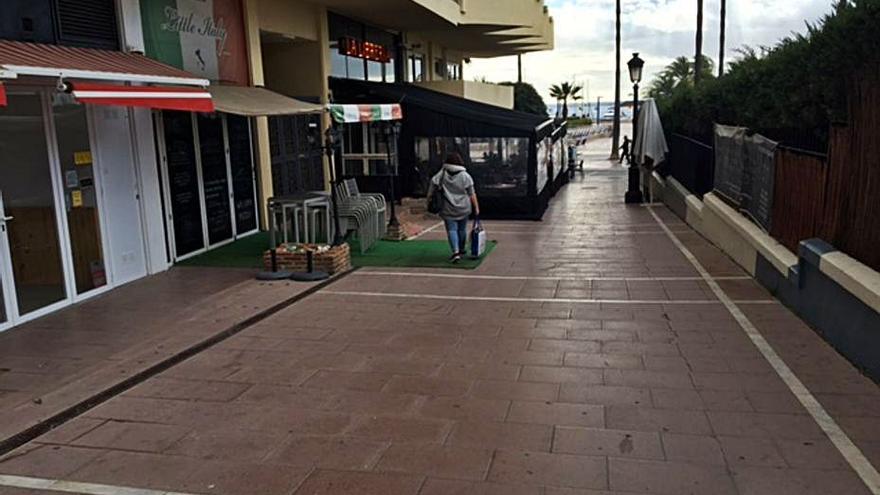 Una vecina pasa delante de negocios cerrados en el paseo marítimo. | L. O.