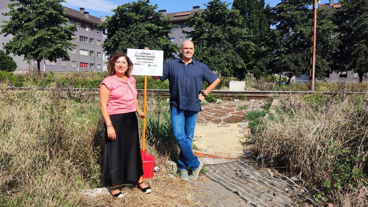 Carmen Eva Pérez y Monchu García, con uno de los carteles de protesta junto a las vías de El Lauredal.