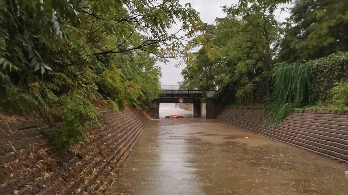 Un coche cubierto de agua en una carretera de Badajoz.