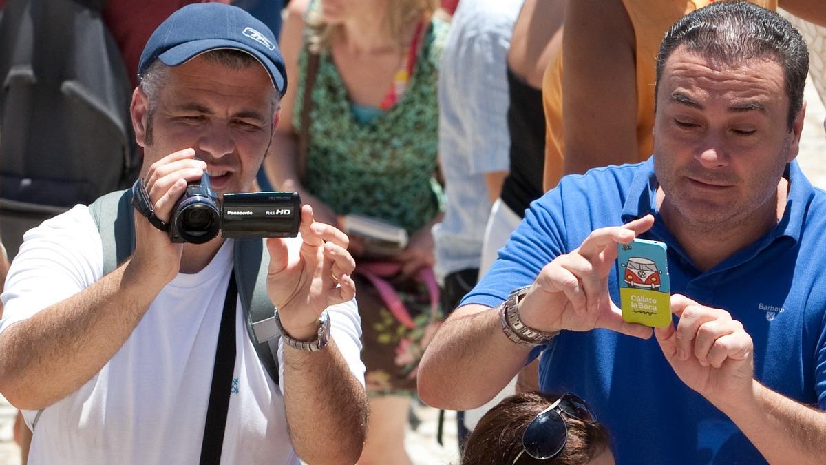 Un turista captura imágenes con su teléfono móvil (derecha) mientras el otro lo hace con una cámara, en Barcelona