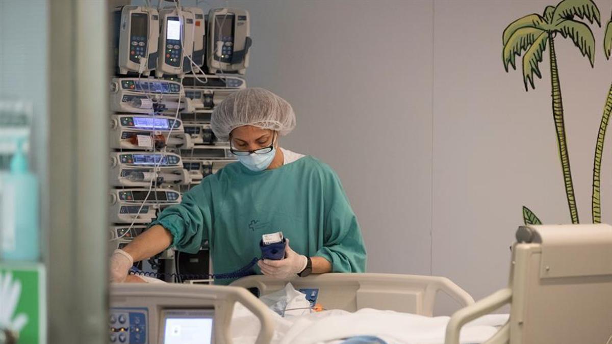 Una sanitaria atiende a un paciente ingresado en una Unidad de Cuidados Intensivos.