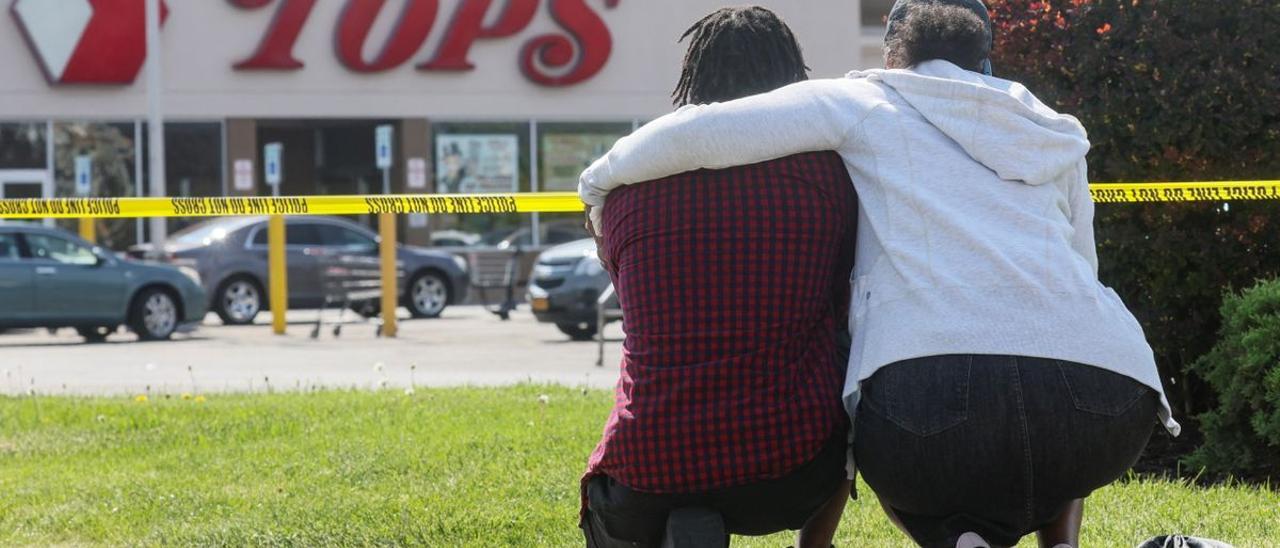 Una pareja arrodillada en las cercanías del supermercado de Búfalo donde se produjo la matanza.