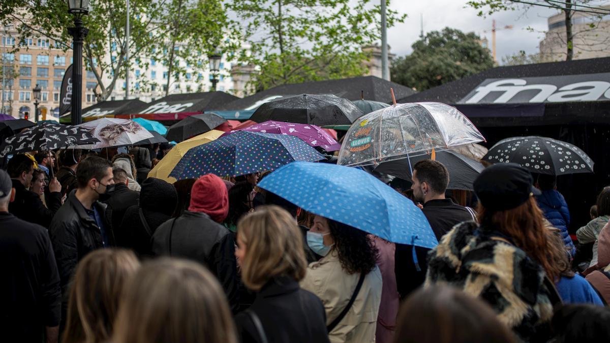 Varias personas, con paraguas, en la feria literaria de Sant Jordi, en el día Internacional del Libro, a 23 de abril de 2022, en Barcelona