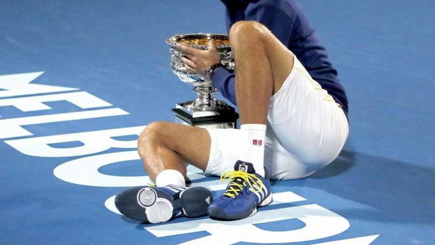 Novak Djokovic posa con su trofeo de campeón sobre la pista azul donde se disputó el torneo.