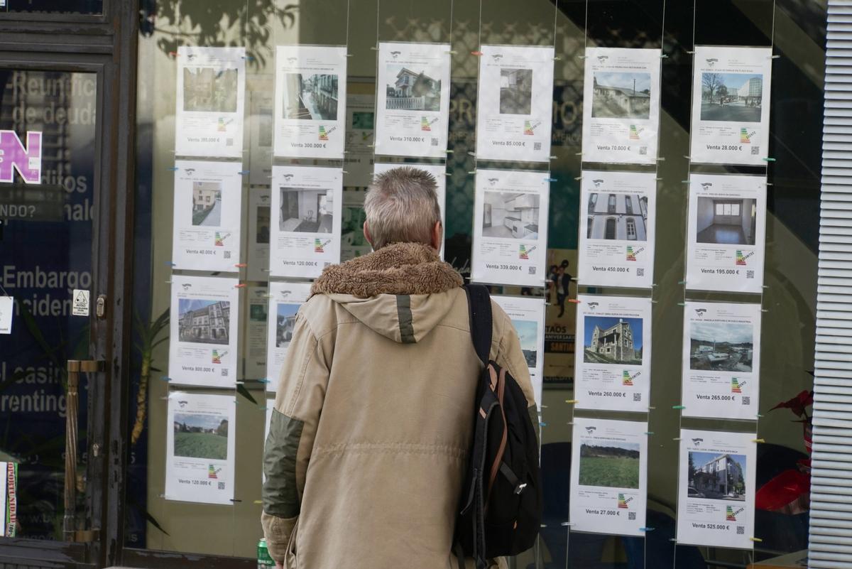 Una persona ojea pisos en alquiler en el escaparate de una inmobiliaria en Santiago