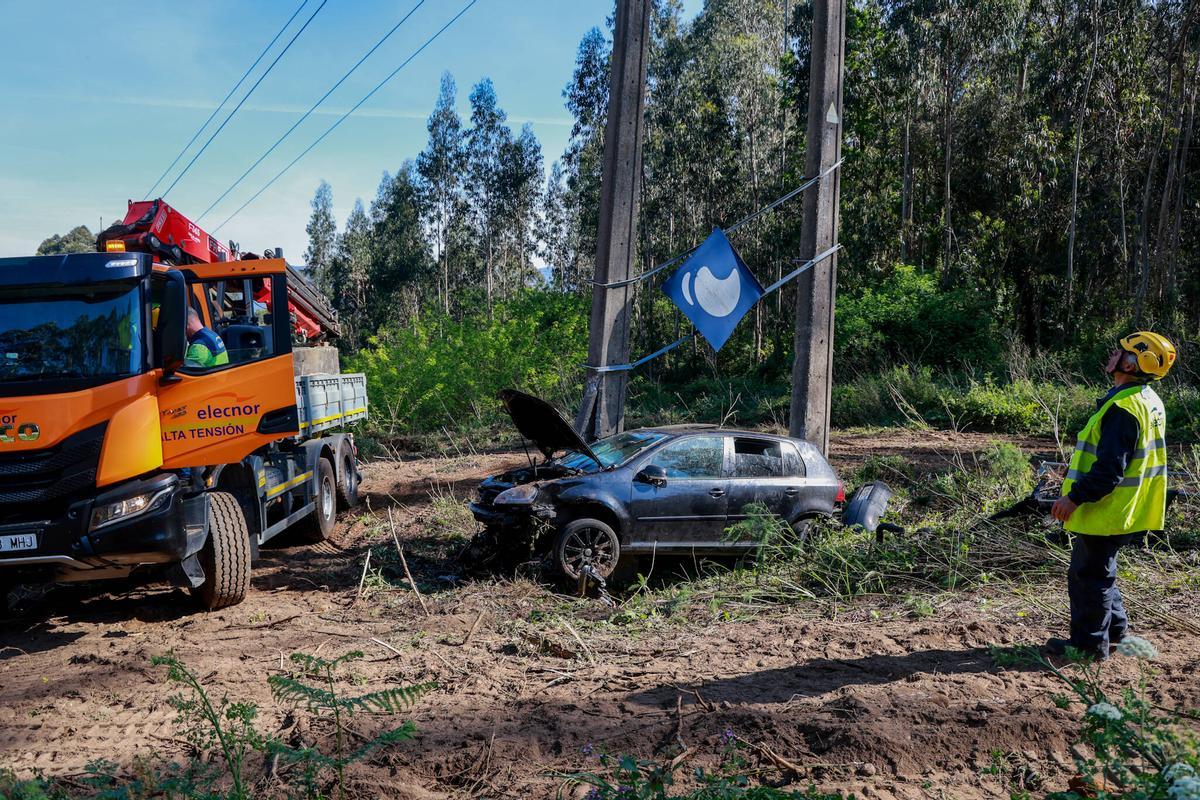 El coche abandonado y operarios con los trabajos para asegurar el soporte del tendido.