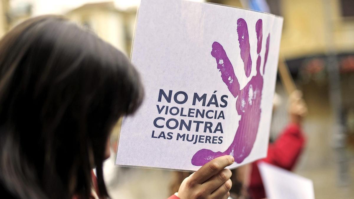 Una mujer camina con un cartel contra la violencia machista.