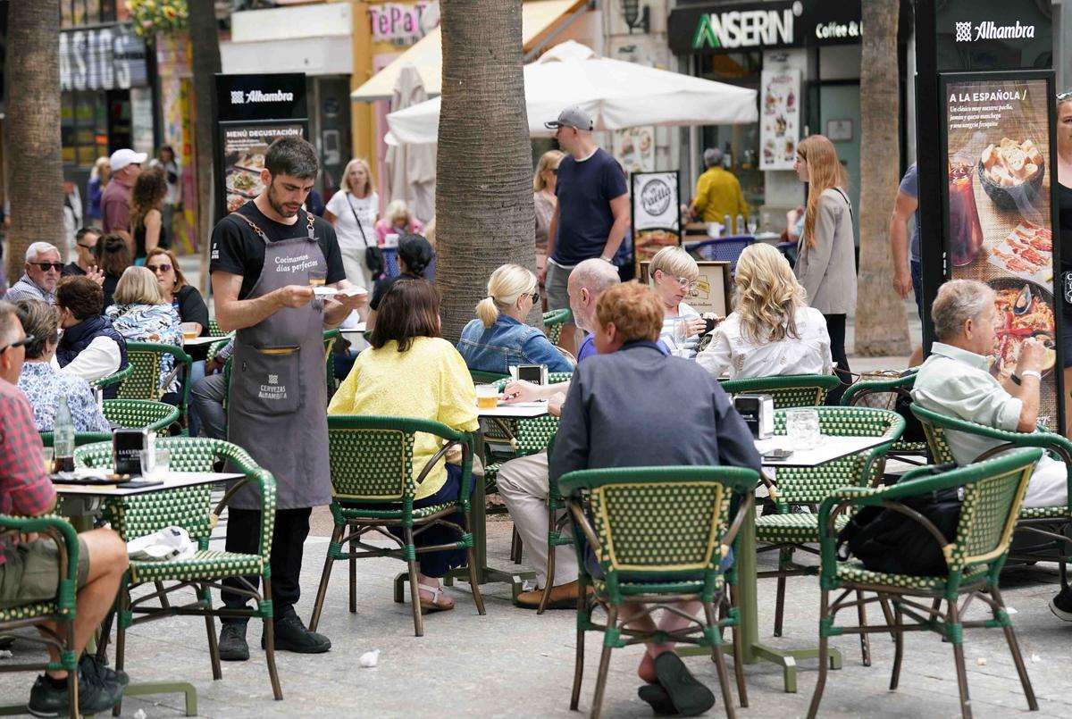 Varios camareros jóvenes sirven a los clientes en las terrazas de los restaurantes en el Centro de Málaga.