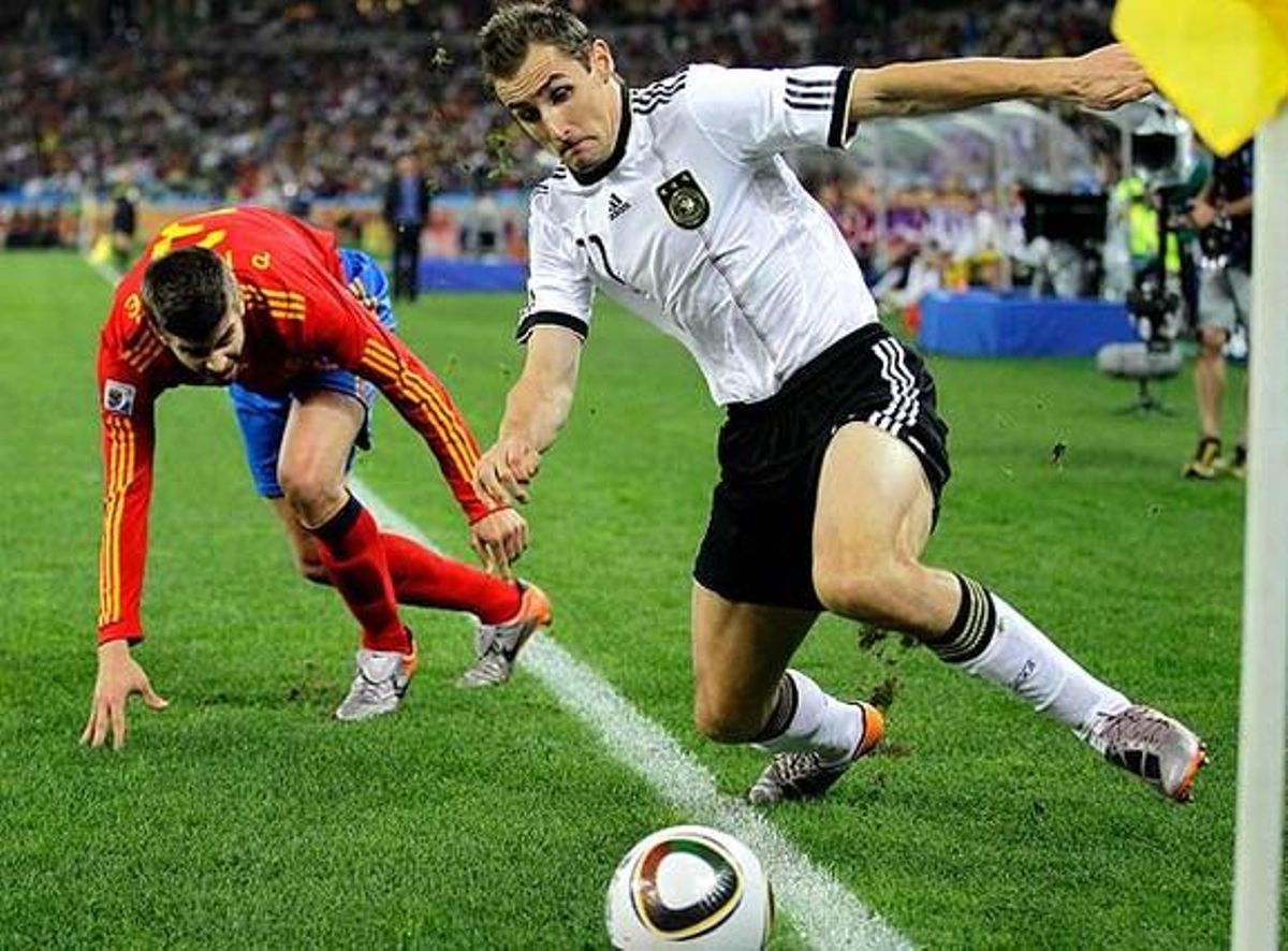 El davanter alemany Miroslav Klose intenta retenir la pilota davant la pressió del defensa espanyol Gerard Piqué.