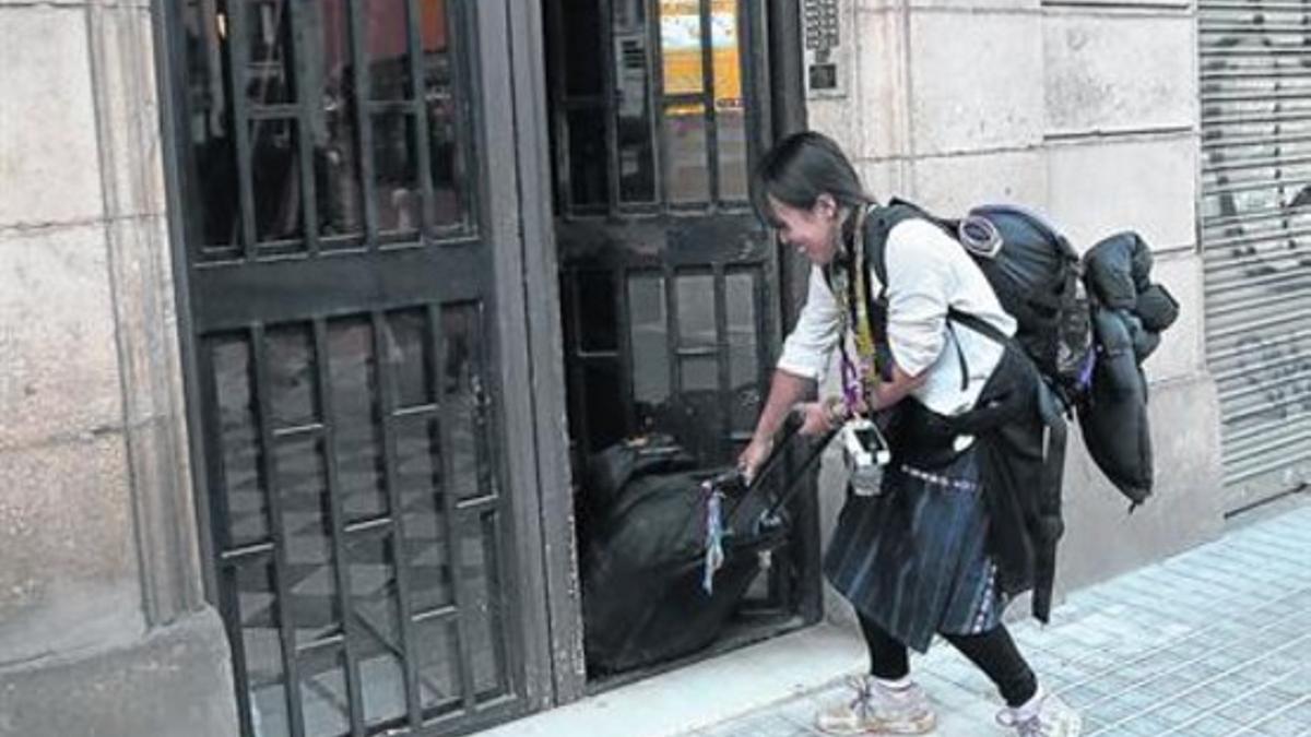 Una joven sale con su equipaje de un inmueble situado en el centro de Barcelona.