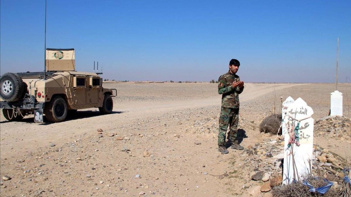 Un soldado afgano reza cerca de una tumba en la provincia de Helmand, este martes.