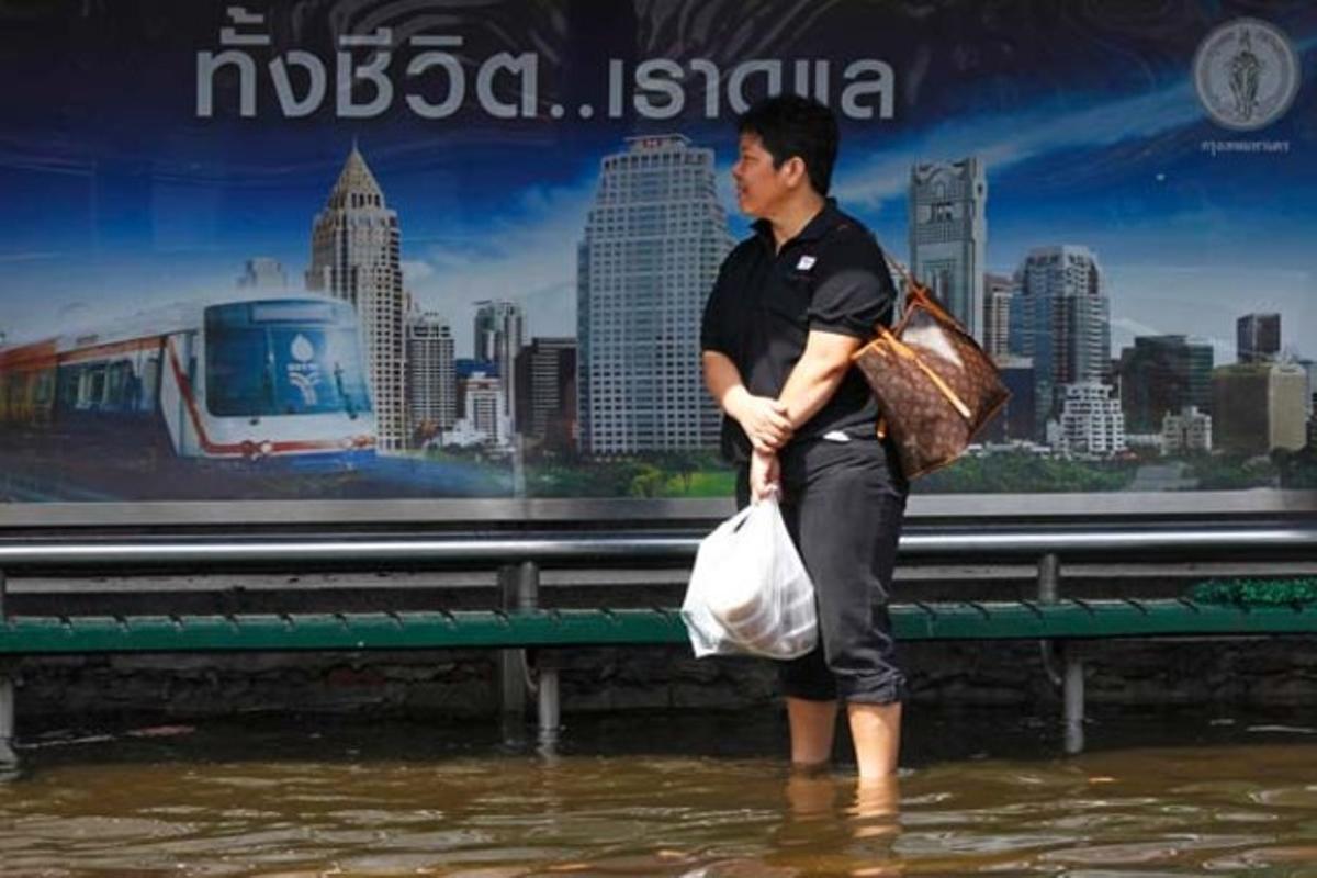 Una dona espera l’autobús en una parada inundada per les pluges a Bangkok, Tailàndia.