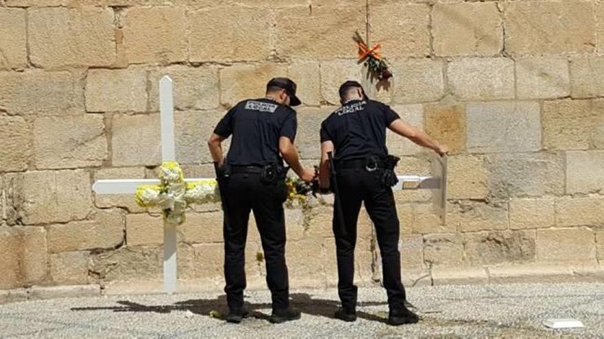 Dos agentes de la Policía Local se llevan la cruz tras haber retirado primero las ofrendas florales.