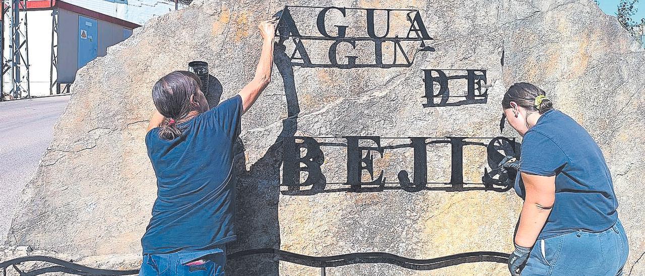 Operarias de la brigada municipal realizan mejoras de pintura en el cartel de la planta envasadora de Agua de Bejís.