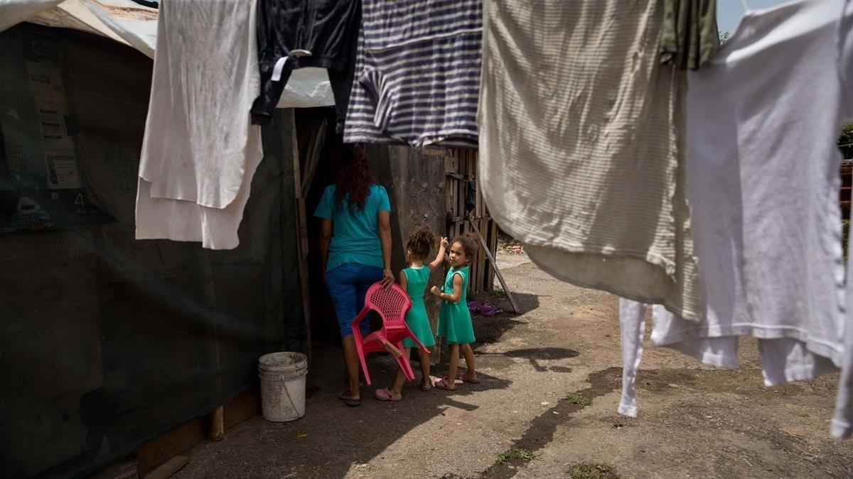 Una mujer y dos niñas entra en una casa en un barrio de chabolas de Caracas, este mes de julio.