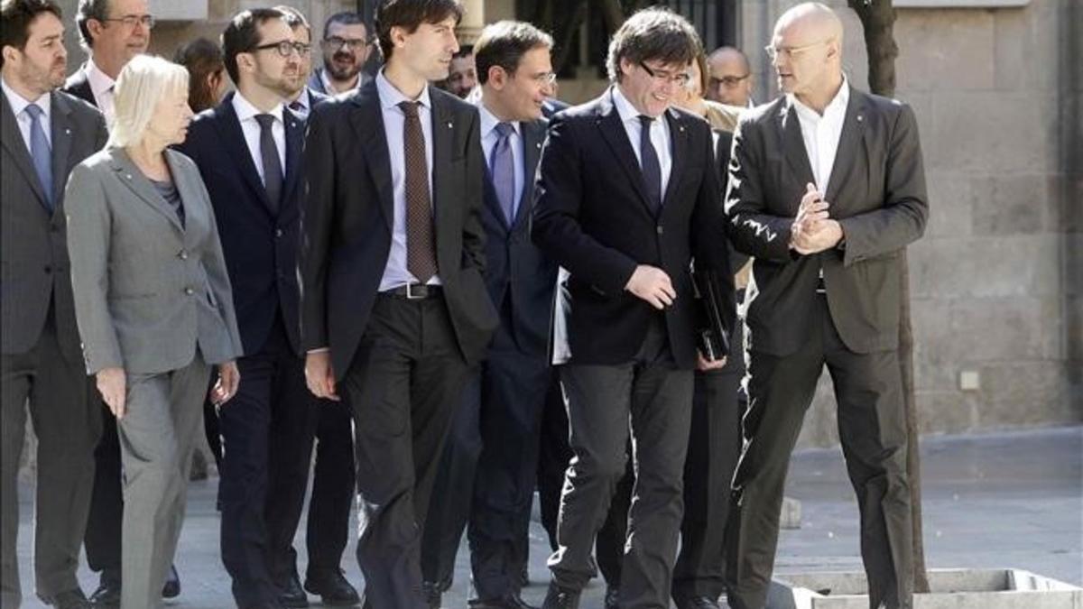 El 'president' Carles Puigdemont conversa con el 'conseller' d'Exteriors, Raül Romeva, junto a los delegados catalanes en el extranjero.