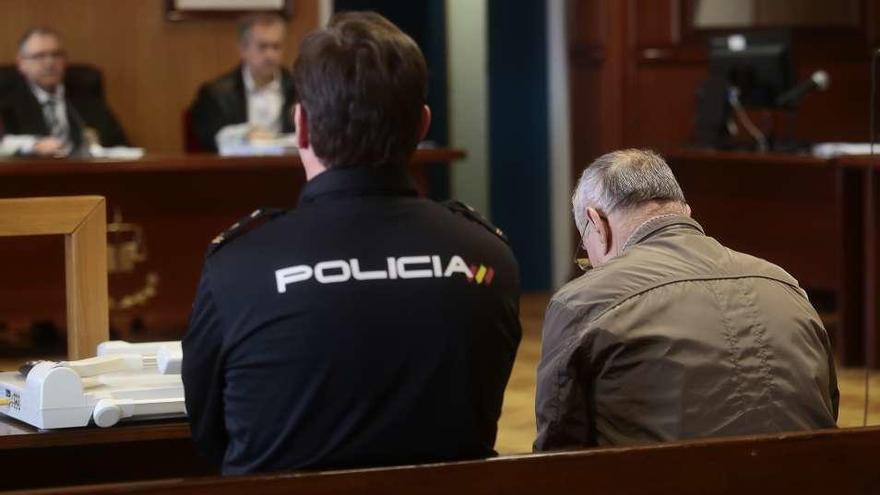 El acusado, de espaldas y custodiado por la Policía, ayer, en la vista celebrada en la Audiencia viguesa. // A. Irago