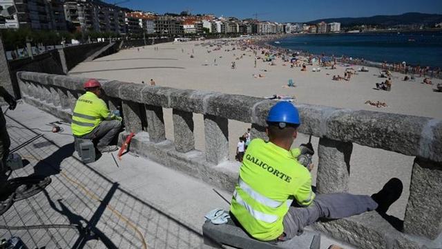 Dos operarios trabajan en la balaustrada.