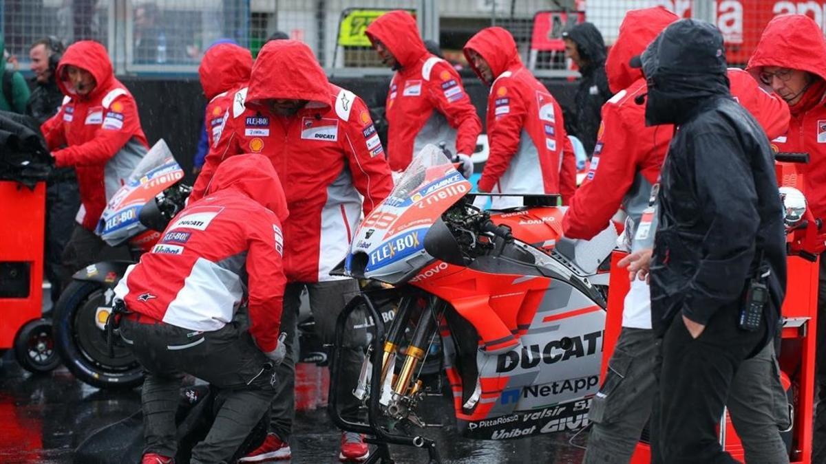Los mecánicos de Ducati retiran la moto de Jorge Lorenzo de la parrilla, inundada, de Silverstone.