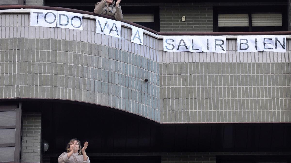 Una mujer despliega un cartel de ánimo en su balcón.