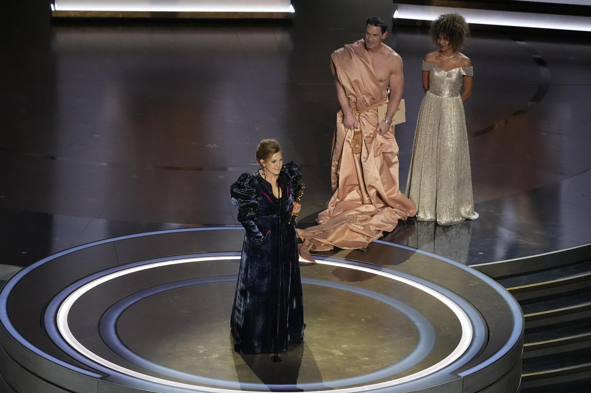 Holly Waddington accepts the award for best costume design for "Poor Things" during the Oscars on Sunday, March 10, 2024, at the Dolby Theatre in Los Angeles. John Cena looks on from right.(AP Photo/Chris Pizzello) Associated Press/LaPresse Only Italy and Spain / EDITORIAL USE ONLY/ONLY ITALY AND SPAIN