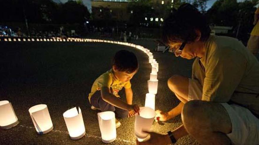 Arriba, un hombre y su hijo colocan una vela en recuerdo a los fallecidos el  11 de marzo. Abajo, manifestantes antinucleares, ayer. i E. KENNEDY / ISSEI KATO