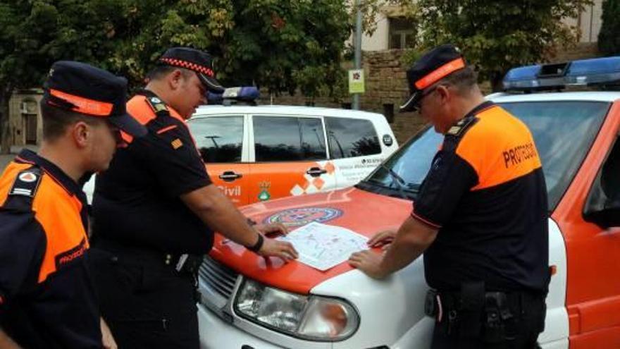 Pla mitjà de tres voluntaris de Protecció Civil mirant un mapa.