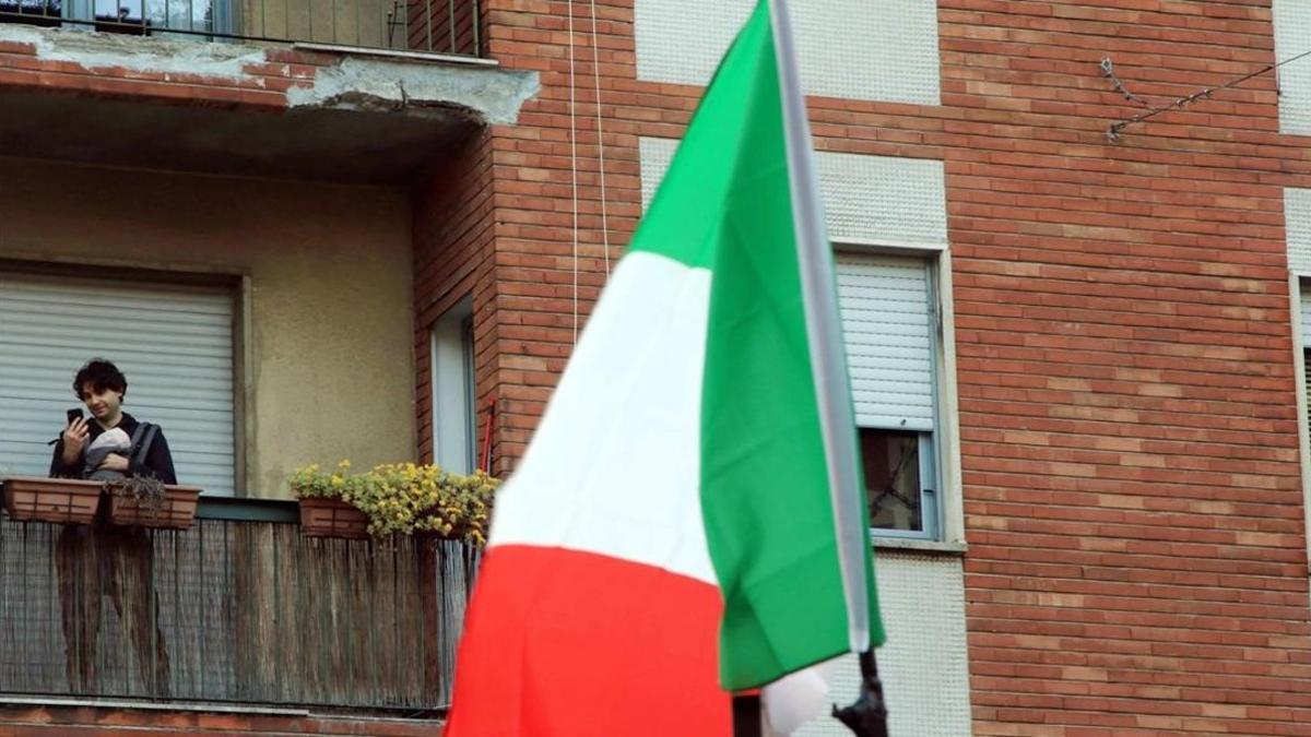 Un ciudadano milanés con su bebé en su balcón.