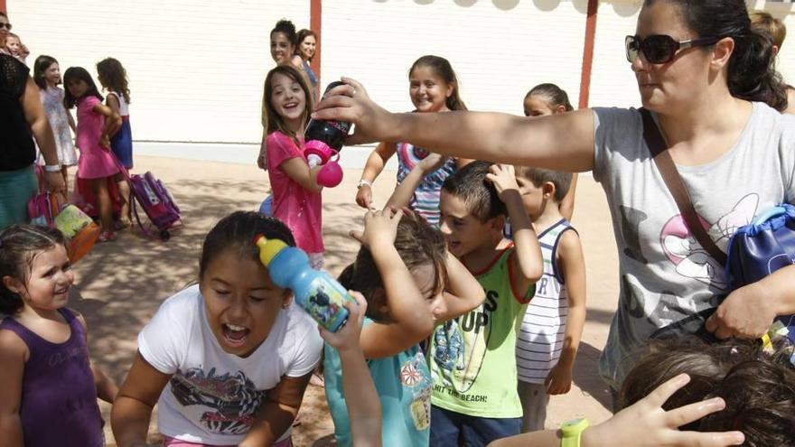 Una madre refresca a los alumnos del colegio público Contraparada de Javalí Nuevo al salir de las clases, en cuyas aulas  no hay aire acondicionado.