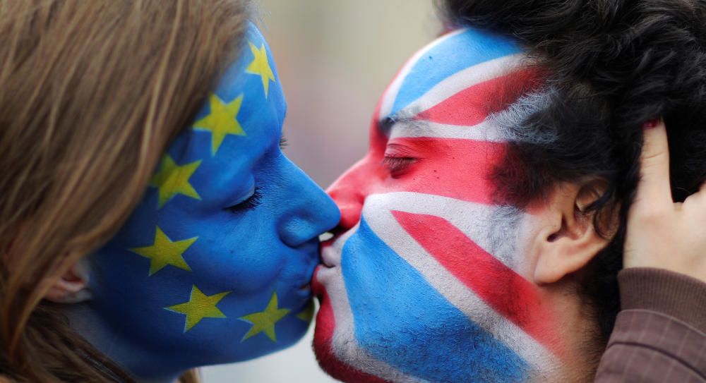 Dos activistas con las caras pintadas de las banderas de Gran Bretaña y la Unión Europea se besan en las puertas de Brandeburgo como protesta contra el Brexit.