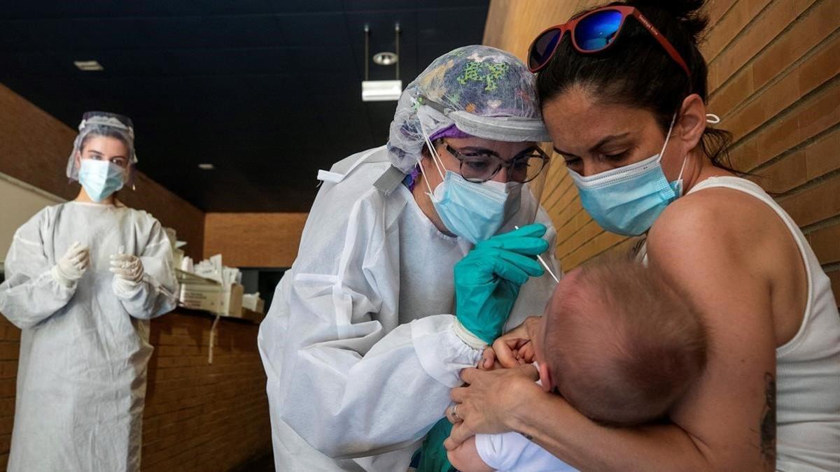 Una sanitaria realiza un test PCR a un niño en un espacio habilitado fuera de un Centro de Salud de la ciudad de Zaragoza, el 1 de julio del 2020