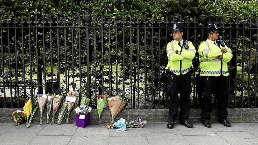 Flors dipositades al lloc de l&#039;atac, que ahir era vigilat per dos agents de Scotland Yard