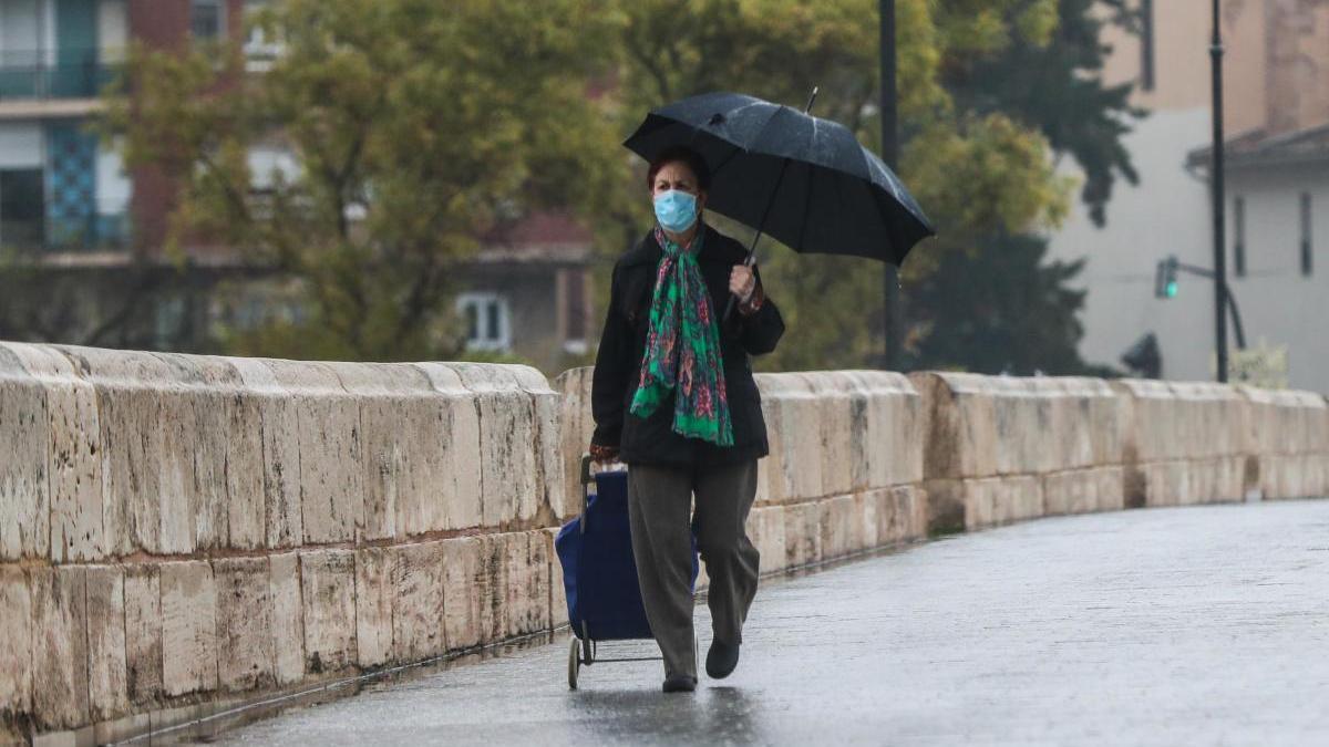 Una mujer camina bajo la lluvia en València.