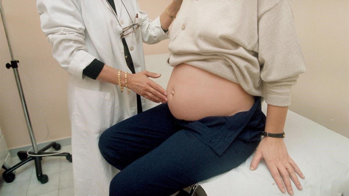 Una doctora examina a una mujer embarazada de seis meses.