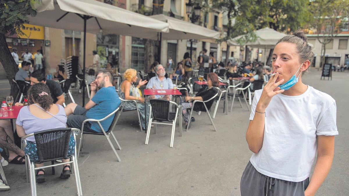 Una mujer, fumando junto a una terraza.