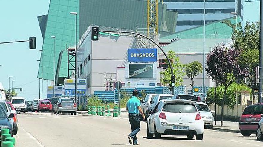 Un joven cruza la calle Alcalde Parrondo, al mediodía de ayer; al fondo, el auditorio.