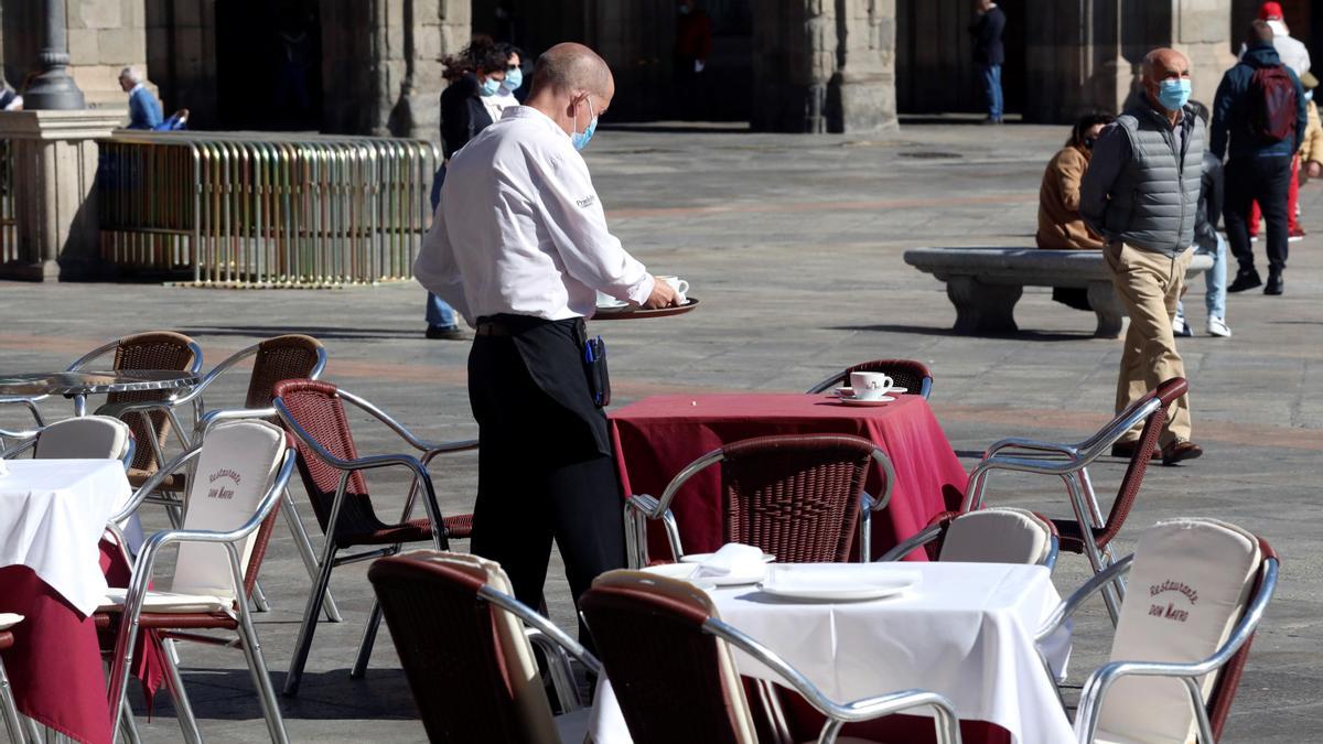 Un camarero recoge una terraza en la Plaza Mayor de Salamanca.