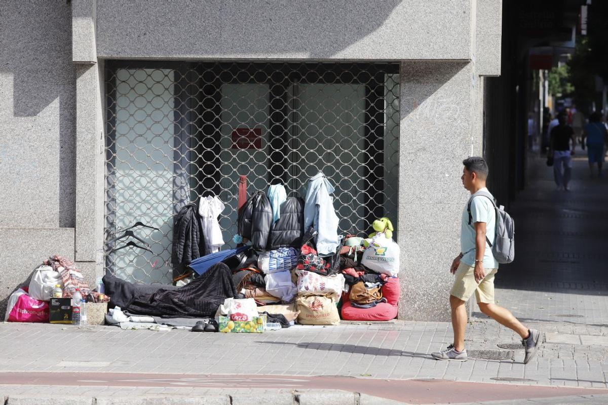 Una persona camina junto a las pertenencias de una persona sin hogar, en Córdoba, este lunes.