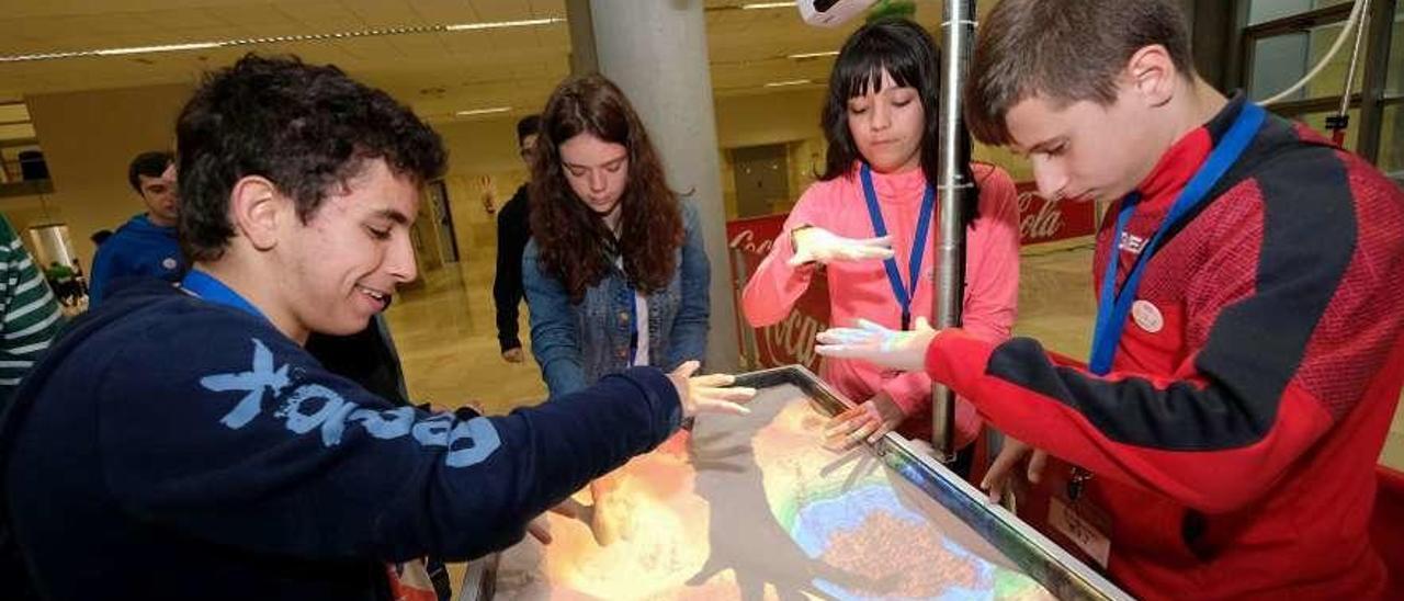 Cuatro estudiantes prueban la caja de arena cartográfica, que utiliza la realidad aumentada.