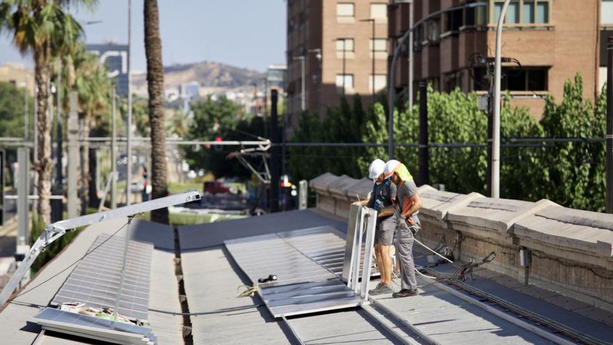 Operarios colocan las placas solares en la cubierta de los antiguos andenes de Murcia, en la sede de Aguas de Murcia