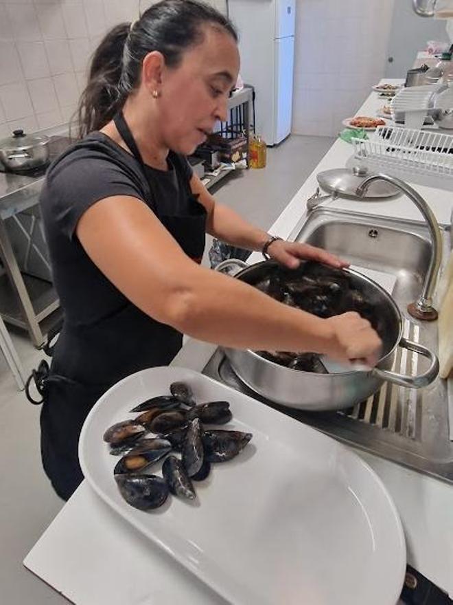 La cocinera a punto de sacar unos mejillones al vapor.