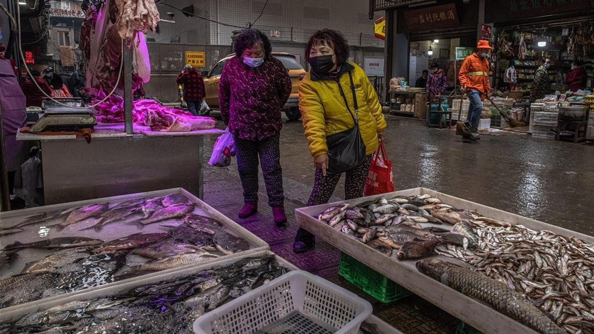 Dos mujeres compran pescado en un mercado de Wuhan, este viernes.