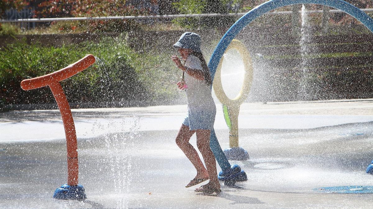 Una niña se refresca en una fuente de Ourense