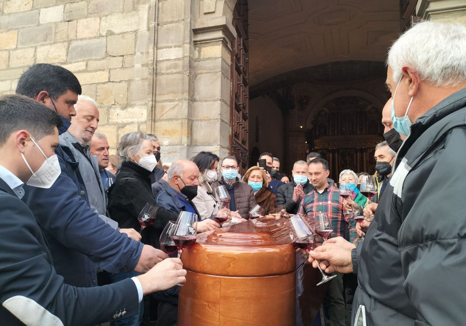 Bodegueros y viticultores de Cangas del Narcea brindan junto al féretro de Antón Chicote, ayer, a la entrada de la basílica, tras el funeral. | A. M. Serrano